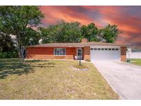 Charming brick home with a manicured lawn and mature trees in a quiet neighborhood at 291 Sagewood Dr, Port Orange, FL 32127