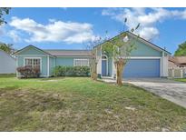 Charming, single-story home featuring a well-manicured lawn, complemented by a colorful exterior and an attached garage at 2937 Garret St, Deltona, FL 32738