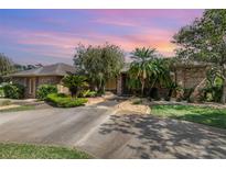 Inviting single-story brick home with a well-manicured lawn, a variety of trees, and a concrete driveway leading to the entrance at 3 Whipper In Cir, Ormond Beach, FL 32174