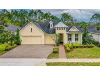 Charming yellow home featuring a three-car garage, landscaped front yard, and inviting entryway at 341 Chelsea Place Ave, Ormond Beach, FL 32174