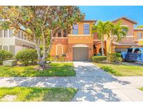 Two-story townhome featuring well-kept landscaping, a two-car garage, and an inviting orange and brown color scheme at 6078 Tivoli Gardens Blvd, Orlando, FL 32829