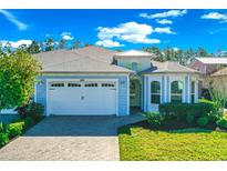 Charming single-story home featuring a paver driveway and two-car garage on a sunny day at 262 Coral Reef Way, Daytona Beach, FL 32124