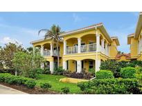 Beautiful yellow two-story condo with white pillars and balconies, set amidst lush landscaping and a blue sky at 2982 S Atlantic Ave, New Smyrna Beach, FL 32169