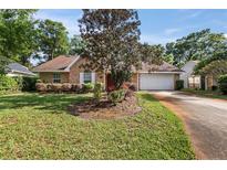 Charming brick home featuring a well-manicured lawn and a spacious two-car garage at 405 Secluded Oaks Trl, Deland, FL 32724