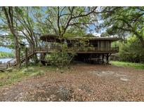 Unique home exterior featuring elevated deck and a covered area underneath, surrounded by lush trees at 4293 Cypress Bnd, Geneva, FL 32732