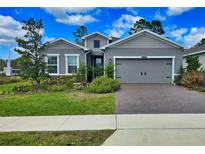 Charming single-Gathering home with gray siding, a well-manicured lawn, and a brick driveway at 1002 Chelan Falls Dr, Deland, FL 32724