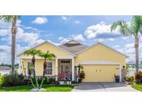 Charming, one-story, yellow home with a well-manicured lawn, palm trees, and an attached two-car garage at 112 Coral Reef Ct, Sanford, FL 32771