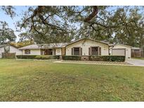 Charming single-story home featuring a manicured lawn, mature trees, and charming curb appeal at 1128 Heidi Ct, Deland, FL 32720