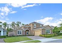 Charming two-story home featuring stone accents, a well-manicured lawn, and a brick paved driveway at 1219 Victoria Hills N Dr, Deland, FL 32724