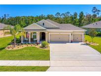 Charming single-story home with a well-manicured lawn, a three-car garage, and a welcoming front porch at 2901 Monaghan Dr, Ormond Beach, FL 32174