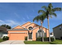 Charming one-story home featuring an attached garage, manicured lawn, and a lovely front yard with palm trees at 320 Conch Key Way, Sanford, FL 32771