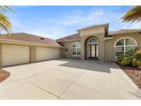 Stunning single-story home featuring a 3-car garage, arched windows, and a spacious concrete driveway at 3470 Tesoro Cir, New Smyrna Beach, FL 32168