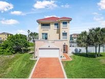 Stunning three-story home with a red tile roof, spacious garage, and lush green lawn at 3817 Islamorada Dr, Ormond Beach, FL 32176
