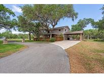 Charming home with a porte cochere and lush landscaping, nestled under mature trees at 800 Hidden Oaks Ln, Oak Hill, FL 32759