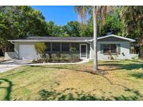 Charming single-story home with a screened porch, attached garage, and lush landscaping at 825 Baltimore Dr, Orlando, FL 32810
