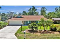 Charming ranch-style home featuring a well-manicured lawn and mature palm trees at 1 Cobblestone Trl, Ormond Beach, FL 32174
