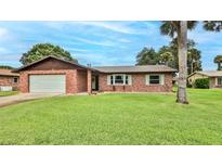 Charming brick home featuring an attached garage and a lush green lawn at 104 Nathan Hale Ct, Daytona Beach, FL 32119