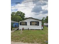 Exterior of a one-story house with white siding and black shutters surrounded by a grassy lawn at 1228 S Parsons Ave, Deland, FL 32720