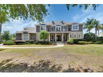 Stately two-story home with a balcony, stone accents, lush lawn and mature trees at 1420 Shady Meadow Ln, Deland, FL 32724