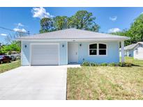 Charming, light blue single-story home featuring an attached garage and well-maintained landscaping at 1598 Montgomery Ave, Daytona Beach, FL 32117