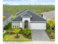 Charming single-story home featuring a manicured front yard and an attached two-car garage with an attractive paved driveway at 225 Mosaic Blvd, Daytona Beach, FL 32124