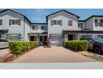 Townhome with brick driveway, attached garage, manicured shrubs, and neutral paint at 258 Rustic Loop, Sanford, FL 32771