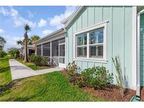 Charming coastal home with light blue siding, manicured lawn, and screened porch at 484 Landshark Blvd, Daytona Beach, FL 32124