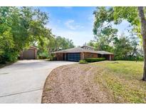Sprawling single-story brick home with an attached garage, long driveway, and a detached garage on a large lot at 6185 Shoreline Dr, Port Orange, FL 32127