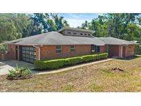 Charming brick home with a modern garage door, well-maintained landscaping, and a contemporary roof design at 6185 Shoreline Dr, Port Orange, FL 32127