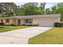 Charming single-story home with a manicured lawn, a large driveway, and an attached two-car garage at 736 Lindenwood W Cir, Ormond Beach, FL 32174
