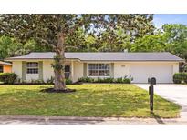 A well-manicured lawn and mature tree enhance the curb appeal of this charming single-story home at 736 Lindenwood W Cir, Ormond Beach, FL 32174