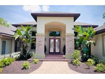 Elegant home entrance featuring a double door, stone pillars and brick walkway lined with tropical plants and lush landscaping at 183 Mcgregor Rd, Deland, FL 32720