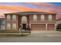 Charming two-story home featuring arched windows, a three-car garage, and lush landscaping against a colorful sunset at 193 Fish Hawk Dr, Winter Haven, FL 33884