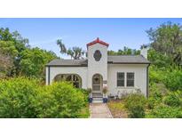 Charming home with stucco exterior, red-tiled tower detail, and inviting front garden with green and yellow bushes at 333 N Kentucky Ave, Deland, FL 32724