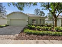 Charming single-story home featuring a two-car garage, brick driveway, and lush landscaping at 417 Victoria Hills Dr, Deland, FL 32724