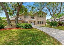 Charming two-story brick home featuring a lush front yard, mature trees, and a paved driveway at 6 Leisure Wood Way, Ormond Beach, FL 32174