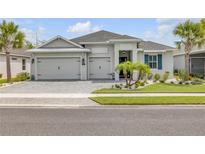 Beautiful single-story home featuring a well-manicured lawn, three-car garage, and charming landscaping with palm trees at 660 Mosaic Blvd, Daytona Beach, FL 32124