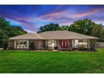 Charming single-story brick home with a well-manicured lawn and a vibrant red front door, inviting and full of curb appeal at 68 Spring Lake Dr, Debary, FL 32713