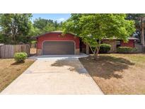 Charming single-story home featuring a garage and a long driveway nestled within a lush green landscape at 688 Cumberland Rd, Deland, FL 32724