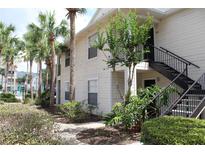 Exterior view of condo building featuring lush landscaping, palm trees, and a community pool in the background at 1083 S Hiawassee Rd # 611, Orlando, FL 32835