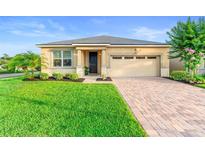 Charming single-story home features a well-manicured lawn, brick driveway, and a welcoming entrance at 2406 Kennington Cv, Deland, FL 32724