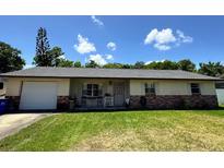 Charming single-story home featuring a brick accent, a lush green lawn and mature landscaping at 2816 Travelers Palm Dr, Edgewater, FL 32141
