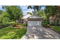 Charming brick home featuring a well-maintained lawn, mature landscaping, and an attached two-car garage at 30 Reflections Village Dr, Ormond Beach, FL 32174