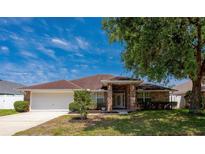 Charming single-story home with brick accents, a well-maintained lawn, and an attached garage at 5463 Carmody Lake Dr, Port Orange, FL 32128