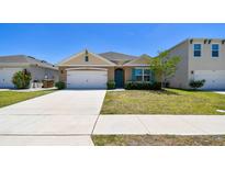 Charming single-story home featuring a well-manicured lawn and a vibrant turquoise-colored front door and window shutters at 5708 Sunbonnet Way, St Cloud, FL 34771