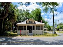 Charming bungalow-style home with screened porch, fenced yard, and mature trees under a blue sky at 580 Ronnoc Ln, New Smyrna Beach, FL 32168