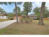 Charming one-story brick home featuring a large front yard with mature trees and a two-car garage at 1075 Burgoyne Rd, Deland, FL 32720