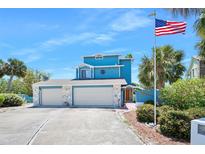 Charming blue home with a three-car garage and an American flag waving proudly at 14 Marsh Ct, Ponce Inlet, FL 32127