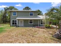 Charming two-story home with a covered porch and mature palm trees at 1560 7Th Ave, Deland, FL 32724