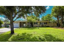 Charming single-story home with lush green lawn and mature trees creating a welcoming curb appeal at 2327 Mulbry Dr, Winter Park, FL 32789